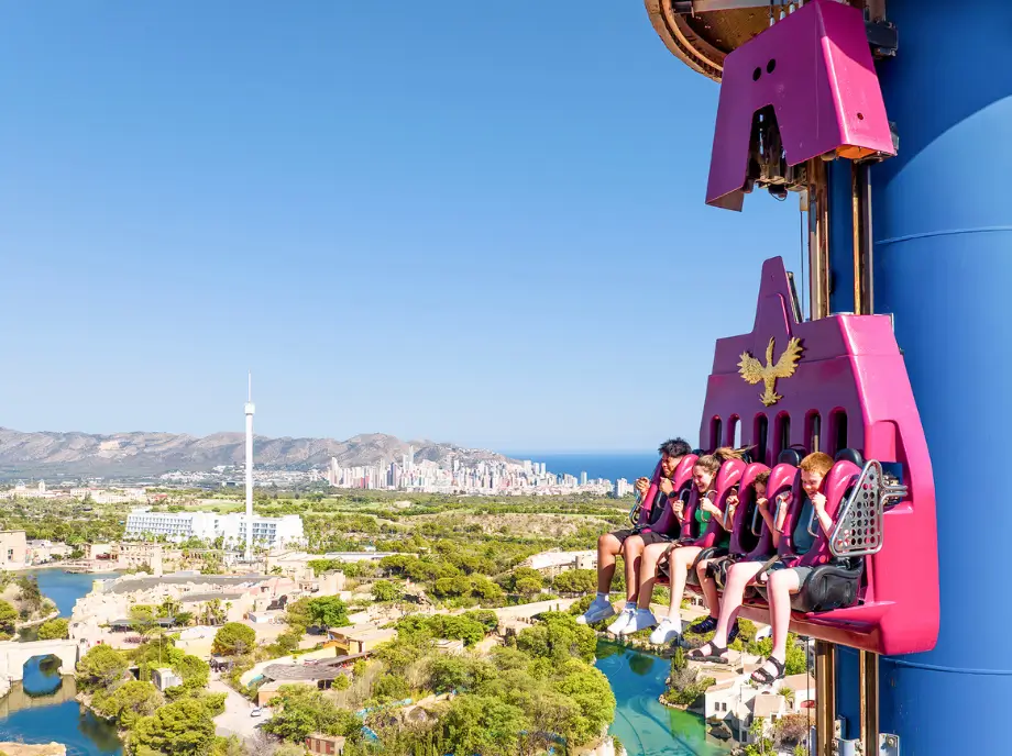 Attraction de chute libre à Terra Mitica Benidorm avec des visiteurs suspendus en hauteur.