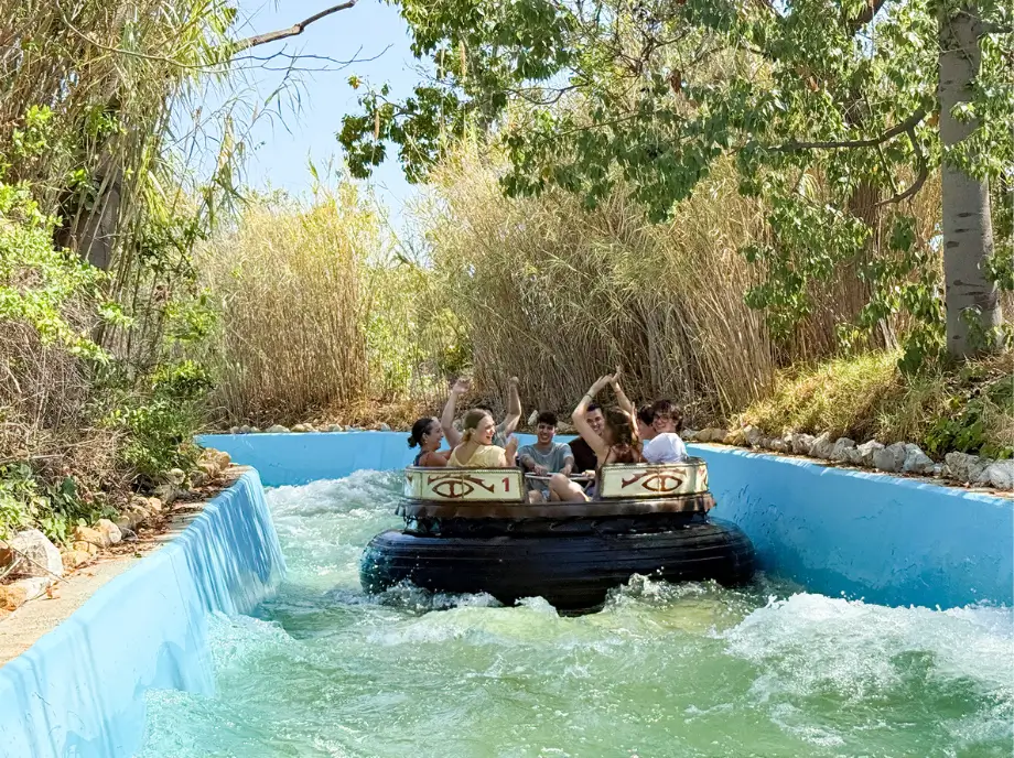 Bateau dans l'attraction aquatique Terra Mitica Benidorm naviguant à travers la végétation et les chutes d'eau.