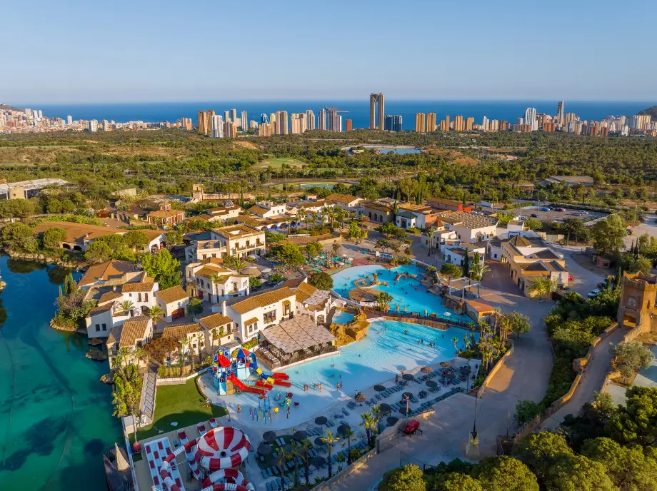 Vue aérienne de Terra Mitica à Benidorm avec les zones aquatiques, les attractions et l'horizon de la ville en arrière-plan.