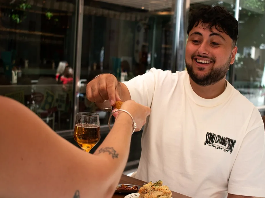 Amigos compartiendo croquetas y cerveza mientras comen tapas en Valencia