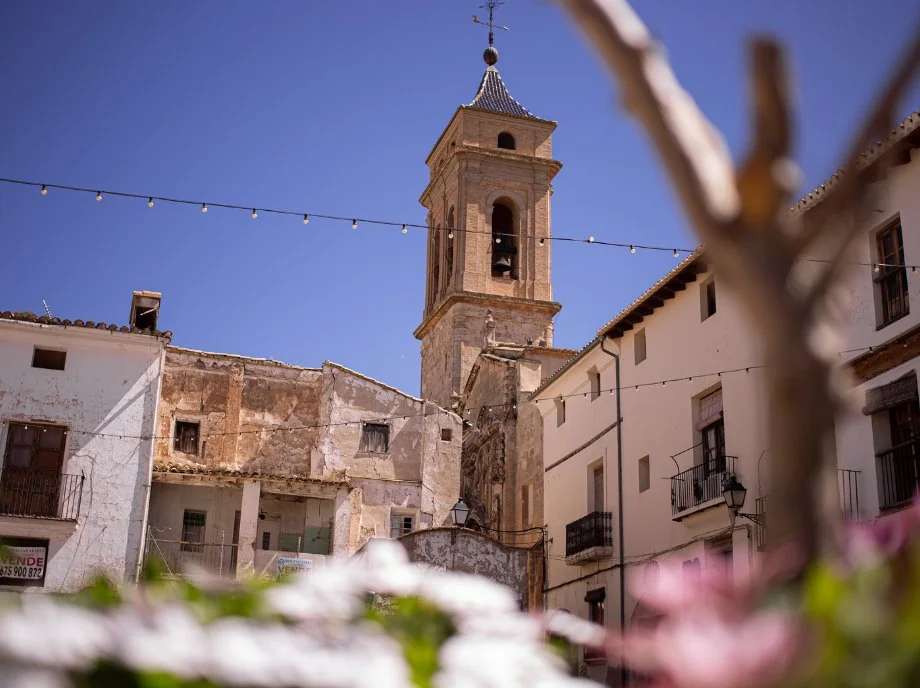 Torre del campanario de iglesia barroca en Utiel-Requena bajo cielo azul.