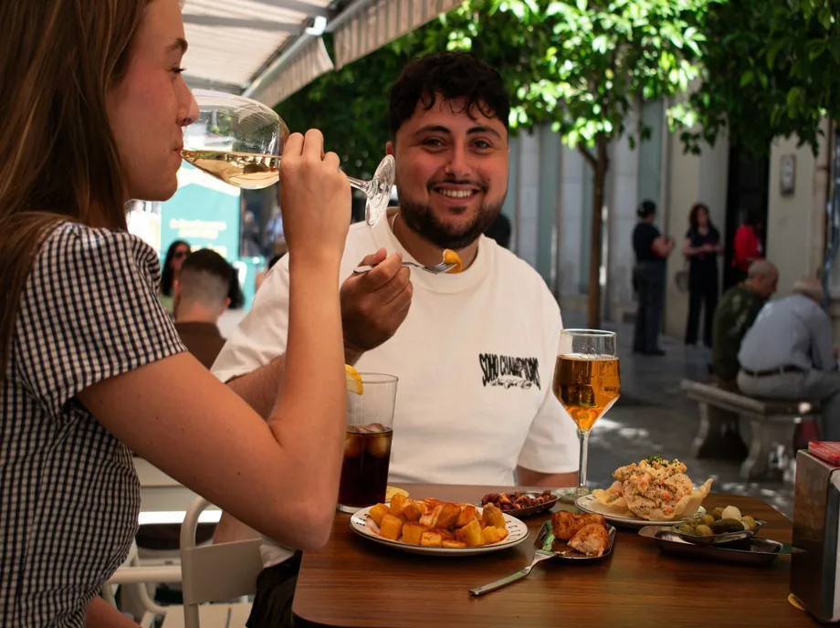 Pareja disfrutando de tapas y vino en una terraza al sol en Valencia