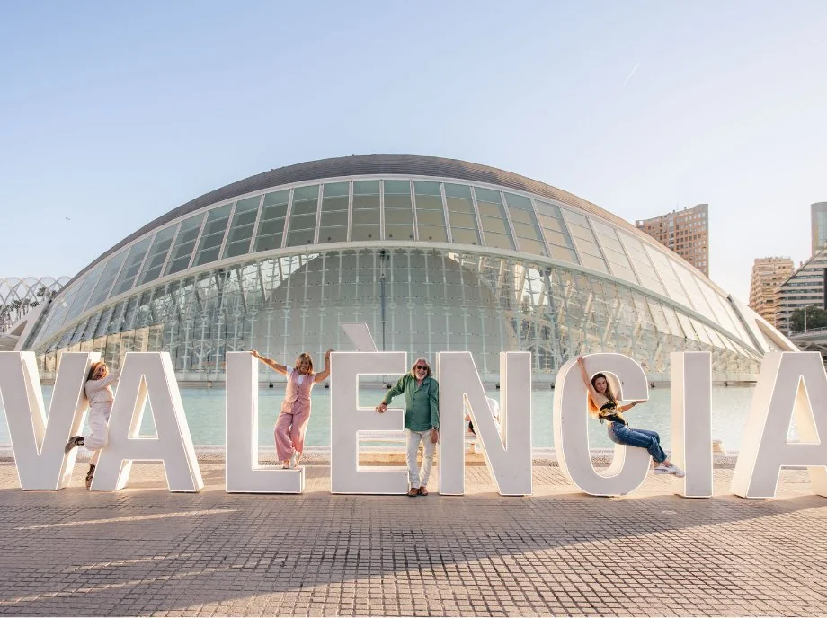Familia saltando junto al letrero gigante de Valencia frente al Hemisfèric, en la Ciudad de las Artes y las Ciencias.
