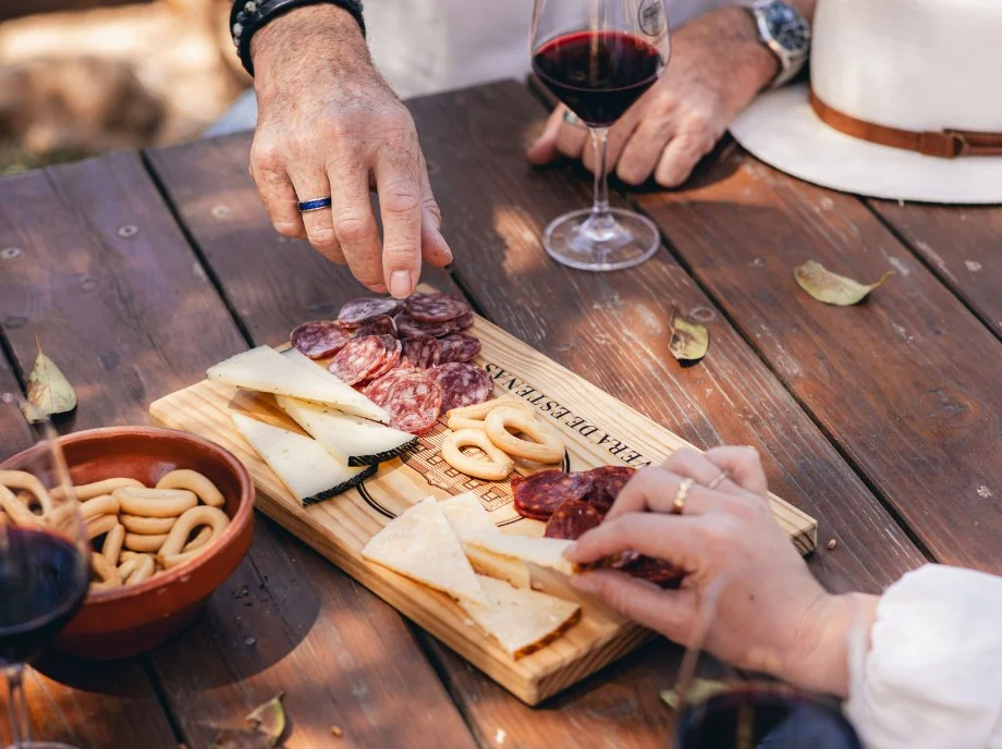 Tabla de embutidos y quesos artesanos con copa de vino tinto en una cata en Requena.