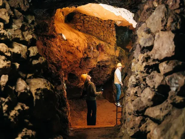 Visiteurs casqués parcourant une galerie rocheuse dans le Parc Miner del Maestrat